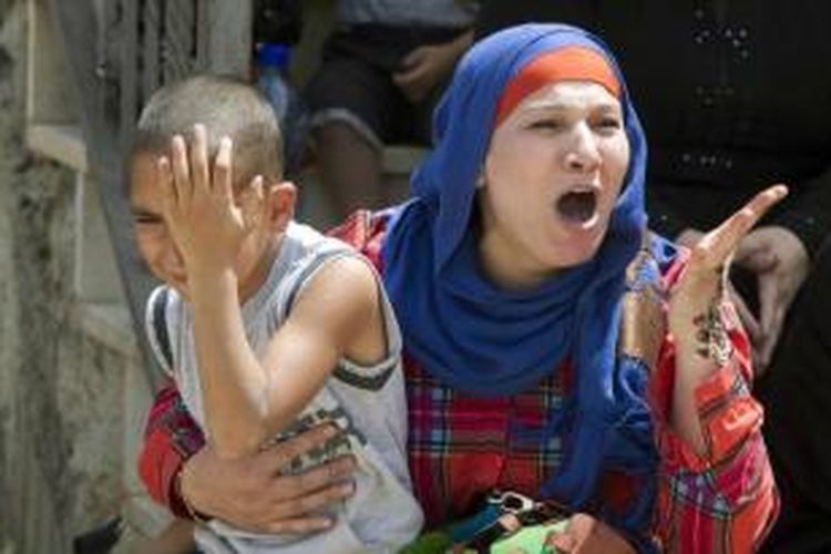 Seorang wanita memegang anaknya saat ia bereaksi ketika buldoser Israel menghancurkan rumah Palestina di lingkungan Arab Yerusalem timur, Beit Hanina, 29 Mei 2013. Rumah warga Palestina yang dibangun tanpa izin sering dibongkar atas perintah Yerusalem