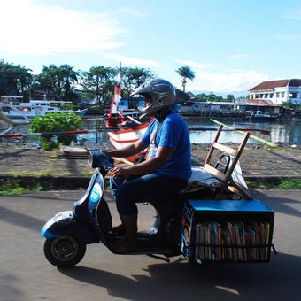 Seorang relawan dari Komunitas Tanah Ombak sedang membawa buku-buku bacaan untuk dipinjamkan kepada anak-anak, Minggu (16/7/2017). Tanah Ombak meluncurkan kegiatan pustaka bergerak yang diberi nama Vespa Pustaka untuk menjangkau anak-anak di Kota Padang yang membutuhkan akses pendidikan lewat buku bacaan.