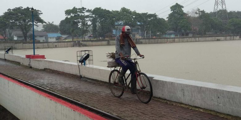 Warga menyeberang di Bendung Pasar Baru di Tangerang yang mengatur debit air Sungai Cisadane, Rabu (28/2/2018).