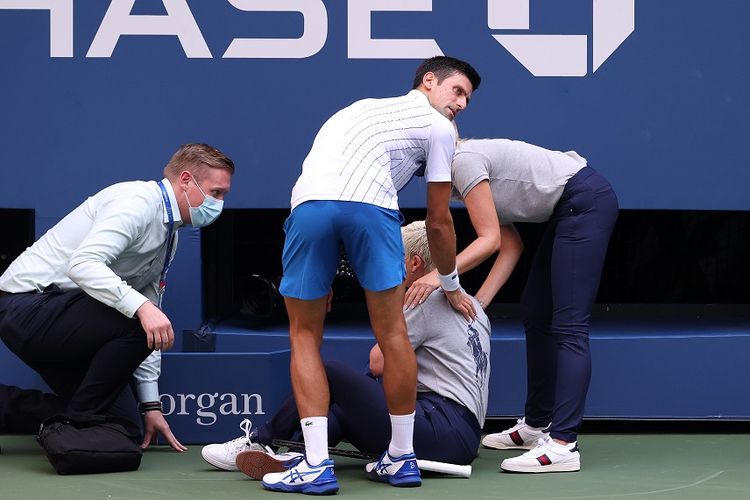 Petenis Novak Djokovic (celana biru) dan hakim garis (duduk) yang terkena pukulan bola dalam laga keempat saat melawan Pablo Carreno Busta dari Spanyol pada US Open 2020 di USTA Billie Jean King National Tennis Center pada 6 September 2020.