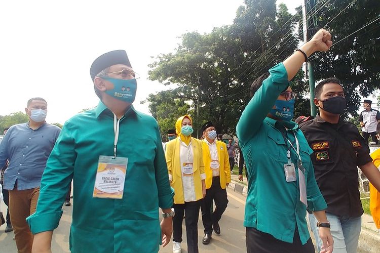 Calon Wali Kota Tangsel Benyamin Davnie dan Calon Wakil Wali Tangsel Pilar Saga Ichsan berjalan kaki menuju kantor KPU Tangerang Selatan sambil membagikan masker pada Sabtu (5/9/2020).