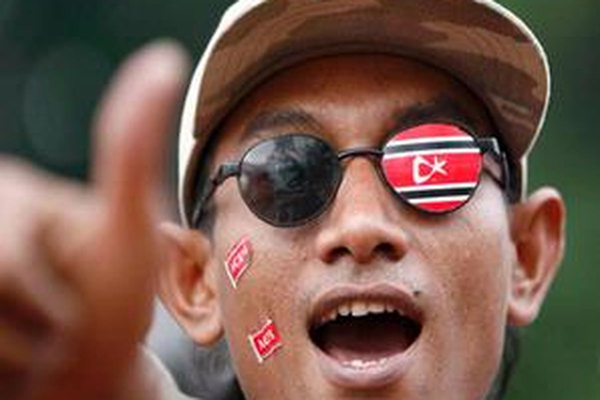 Seorang simpatisan Partai Aceh (PA), menempelkan logo partai tersebut di wajahnya saat tiba di Kota Banda Aceh untuk menyambut kedatangan petinggi Gerakan Aceh Merdeka (GAM), Tgk Dr Muhammad Di Tiro.