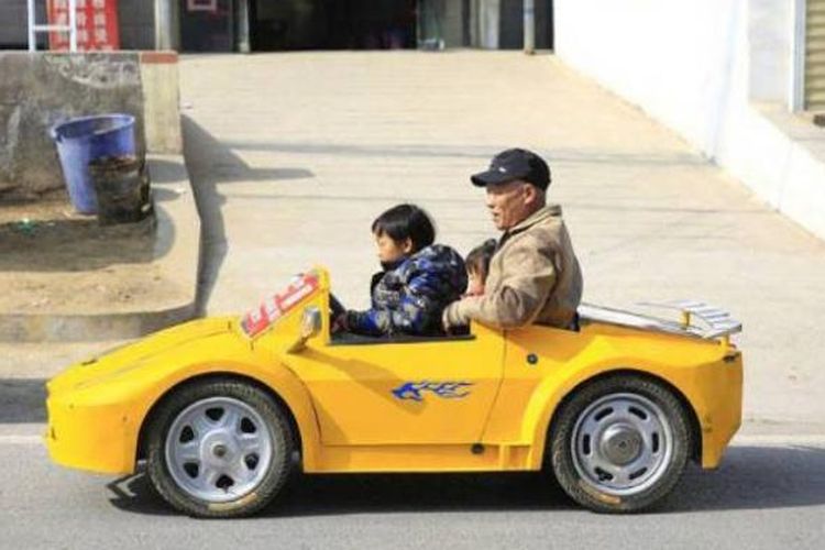 Guo Liangyun (55) menunggangi Lamborghini mini ciptaannya bersama sang cucu.