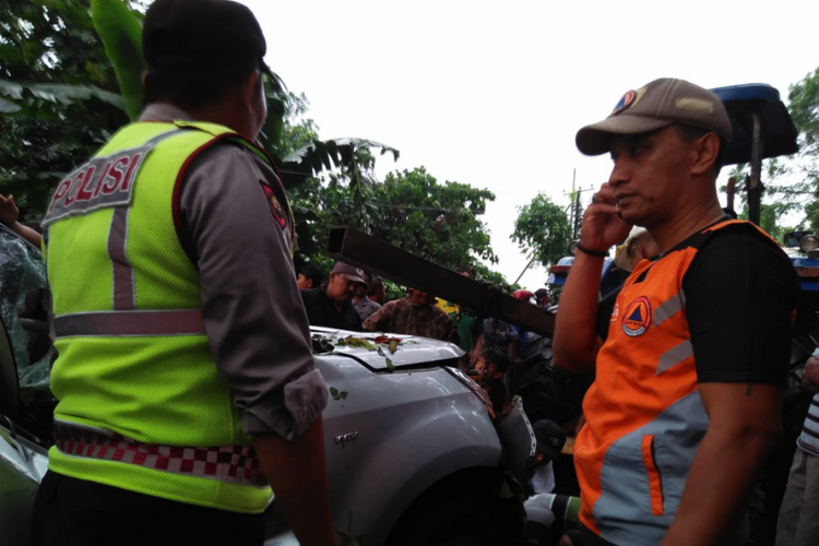 Petugas polisi dan BPBD saat penanganan awal mobil yang tertimpa pohon di Alas Jamban Kecamatan Plosoklaten, Kabupaten Kediri, Jawa Timur, Minggu (18/11/2018).