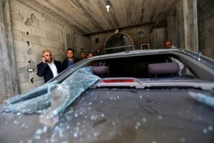 Fayez Abu Eitta (kiri), seorang pemimpin Fatah di Jalur Gaza, berbicara lewat telepon setelah dia memeriksa kerusakan mobilnya akibat serangan bom di kediamannya di Beit Lahiya, Jalur Gaza. Setidaknya 10 ledakan menghantam kediaman dan mobil milik para pemimpin Fatah di Jalur Gaza.