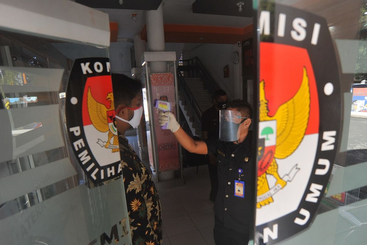 Petugas menggunakan pelindung wajah mengecek suhu tubuh staf yang datang di Kantor Komisi Pemilihan Umum (KPU) Sumatera Barat, di Padang, Jumat (10/7/2020). KPU pusat menyiapkan perlengkapan APD dan fasilitas kesehatan untuk panitia dan peserta pemilu di daerah sebagai upaya penerapan protokol kesehatan COVID-19 selama Pilkada serentak 2020. ANTARA FOTO/Iggoy el Fitra/pras.