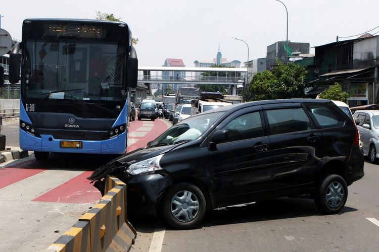 Sebuah bus Transjakarta melintas di dekat mobil yang menabrak separator busway di Jakarta, Jumat (6/10). Tidak ada korban jiwa dalam kecelakaan yang disebabkan oleh sopir mengantuk tersebut. ANTARA FOTO/Rivan Awal Lingga/nz/17