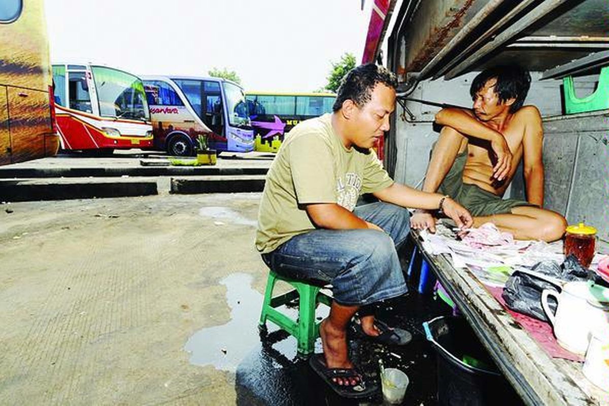 Sopir dan kenek bus Lampung Jaya jurusan Pulo Gadung-Padang, Buyung Kemerun (34) dan Ujang (35), memanfaatkan ruang bagasi sebagai tempat beristirahat dan makan di Terminal Pulo Gadung, Jakarta Timur, Jumat (11/9/2009). Oleh karena penumpang sepi, mereka telah menunggu di Terminal Pulo Gadung selama 12 hari. Mereka berharap dua hari lagi penumpang yang merupakan pemudik akan penuh.