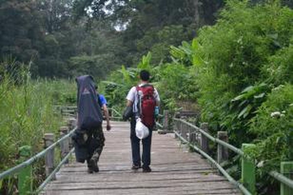 Pendaki membawa kantung sampah melalui jalur jembatan saat pendakian Gunung Gede, Bogor, Jawa Barat