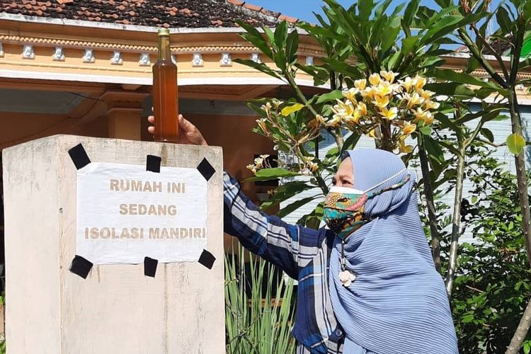 Seorang ibu menaruh jamu tradisional racikan di pagar rumah warga yang sementara menjalani isoman karena positif Covid-19. Ibu-ibu di Dusun Perkul, Desa Sambirejo, Kecamatan Jiwan, Kabupaten Madiun, Jawa Timur, meramu jamu yang bahan-bahannya didapatkan dari pekarangan atau kebun untuk menguatkan imun warga isoman.