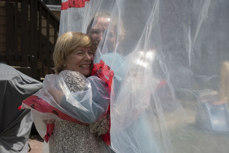 Carolyn Ellis (kanan) memeluk ibunya, Susan Watts, menggunakan tirai plastik yang ia buat sebagai persembahan Hari Ibu di Guelph, Ontario, Kanada, (16/5/2020). Melepas rindu di tengah pandemi, orang-orang menggunakan tirai plastik sebagai solusi memeluk tanpa bersentuhan langsung guna meminimalisir risiko penularan virus corona (Covid-19).