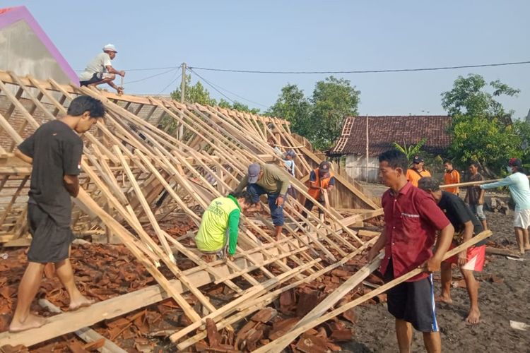 Nampak warga bergotong royong membantu memperbaiki rumah warga Desa Tulung, Kecamatan Saradan yang ambruk diterjang hujan disertai angin kencang.