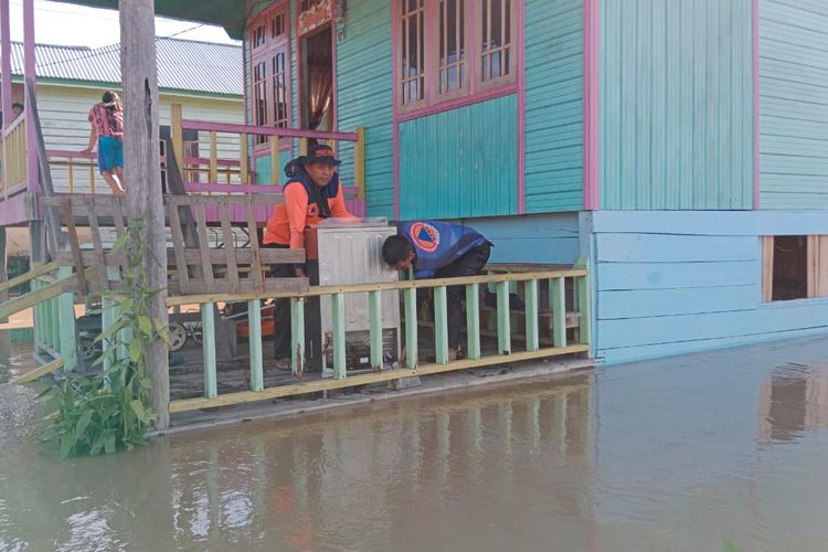 Petugas BPBD Nunukan Kaltara, sedang melakukan pendataan sekaligus membantu korban banjir untuk mengevakuasi barang barang warga