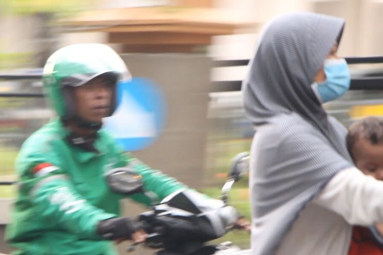 Seorang pengendara motor, membawa serta anaknya tanpa mengenakannya masker. Padahal Anak anak sangat rentan tertular covid19.