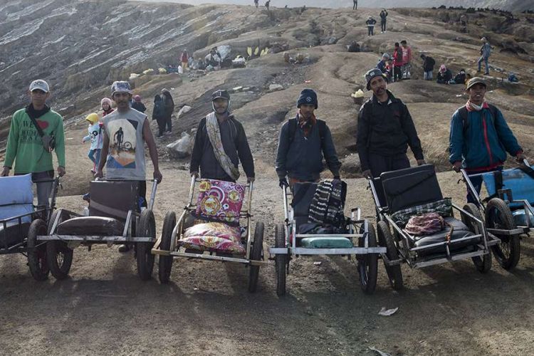 Penambang belerang (dari kiri) Pusinto, Hartono, Sudiyono, Ahmad Santoso, Hariyono dan Sholeh Hidayat berfoto  bersama dengan taksi atau troli saat menunggu pendaki yang akan menggunakan jasa mereka di puncak Gunung Ijen, Banyuwangi, Jawa Timur, Sabtu (23/6/2018). Selain memudahkan pendaki, sejumlah penambang belerang mengakui membuka jasa taksi tersebut untuk mencari uang tambahan dengan memasang tarif berkisar Rp 800 ribu - Rp 1,2 juta per orang.