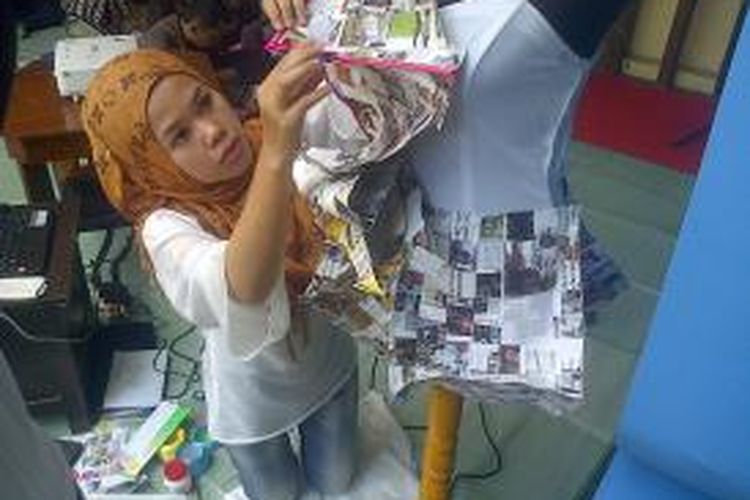 Dewi Mustika Sari (25),Salah seorang peserta Workshop Recycle Fashion and Craft yang digelar di Bandung Creative City Forum Jalan Purnawarman Kota Bandung, tengah sibuk merangkai potongan kertas dari majalah bekas menjadi sebuah pakaian wanita, Jumat (23/8/2013). 