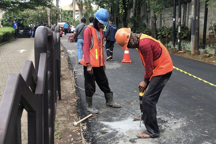 Pekerja proyek melubangi aspal jalan yang menutup sumur resapan di Jalan Lebak Bulus III, Cilandak, Jakarta Selatan yang sempat rusak dan ditutup aspal pada Minggu (5/11/2021) sore.