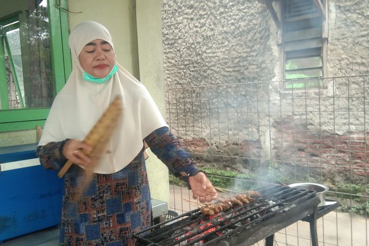 Eneng Komariah saat tengah membakar sate, Sabtu (24/12/2022).