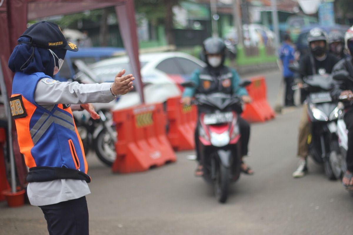 Seorang petugas tengah mengatur lalu lintas kendaraan di kawasan tugu Lampu Gentur Cianjur, Jawa Barat, pada momen mudik lebaran 2022.