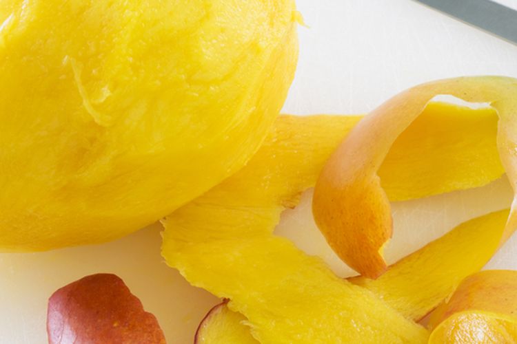 Ilustrasi mengupas mangga. Kulit mangga dapat digunakan sebagai pupuk tanaman. 