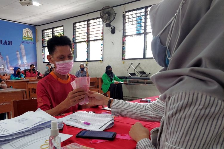 Saiful, warga Kebon Besar, Batuceper, Kota Tangerang, tengah menerima bantuan sosial sebesar Rp 300.000 di SMAN 7 Kota Tangerang, Rabu (25/8/2021).