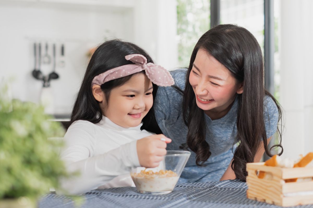 Ilustrasi seorang ibu memberi sarapan sereal untuk anak