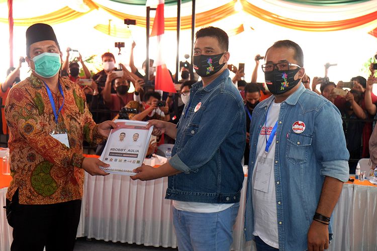 Pasangan bakal calon Wali Kota dan Wakil Wali Kota Medan, Bobby Nasution (tengah) dan Aulia Rahman (kanan) menyerahkan berkas kepada Ketua KPU Medan Agussyah Damanik (kiri) saat mendaftar sebagai calon Wali Kota dan Wakil Wali Kota di Medan, Sumatera Utara, Jumat (4/9/2020). Bobby Nasution dan Aulia Rahman mendaftar sebagai calon Wali Kota dan Wakil Wali Kota Medan yang diusung PDI Perjuangan, Partai Gerindra, Partai Golkar, PPP, Partai NasDem, PAN, Partai Hanura dan PSI.