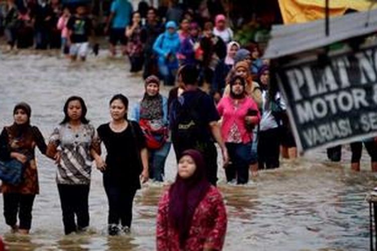 Sejumlah buruh melintasi genangan banjir di Jalan Raya Dayeuhkolot, Kabupaten Bandung, Jawa Barat, saat pulang kerja, Jumat (19/4/2013). Ribuan pemukiman warga, bahkan kawasan pertokoan dan pasar, di wilayah Dayeuhkolot serta pemukiman warga di Baleendah sudah tiga pekan terendam banjir luapan Sungai Citarum. Jalur lalulintas yang terputus memaksa warga, termasuk para buruh pabrik di kawasan tersebut, harus melintasi genangan air untuk menuju pemberhentian kendaraan dengan jarak berjalan kaki sekitar 2 kilometer. 
