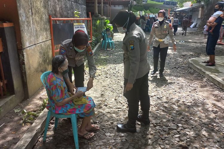 Petugas polwan saat membantu lansia dalam pencairan BPNT di kantor pos Kota Kediri, Jawa Timur,Rabu (23/2/2022).