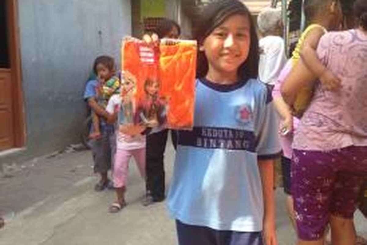 Zahra (11), siswa kelas 5 SD Negeri Kedoya Utara 09, Kebon Jeruk, Jakarta Barat, memamerkan kaos dengan gambar kartun film Frozen yang diberikan Presiden RI Joko Widodo, Selasa (1/9/2015). 