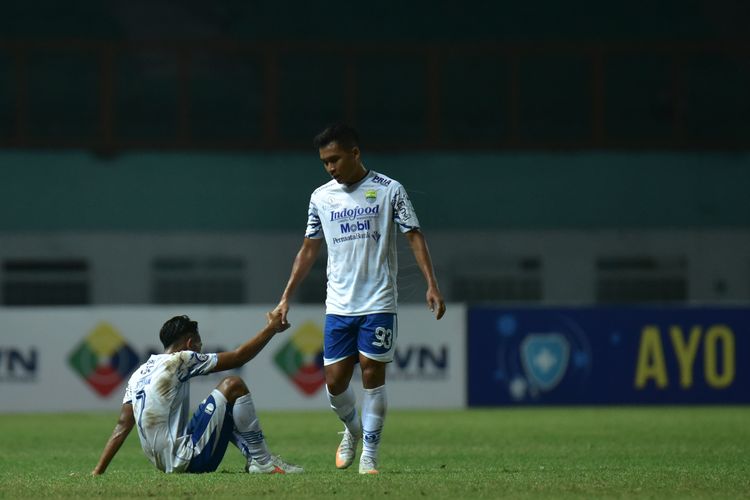 Winger Persib Bandung, Erwin Ramdani (berdiri), membantu rekan setimnya Beckham Putra Nugraha (duduk) untuk bangkit setelah Persib ditahan Persikabo 1973 dengan skor 0-0 di Stadion Wibawa Mukti, Cikarang, Senin (27/9/2021). 