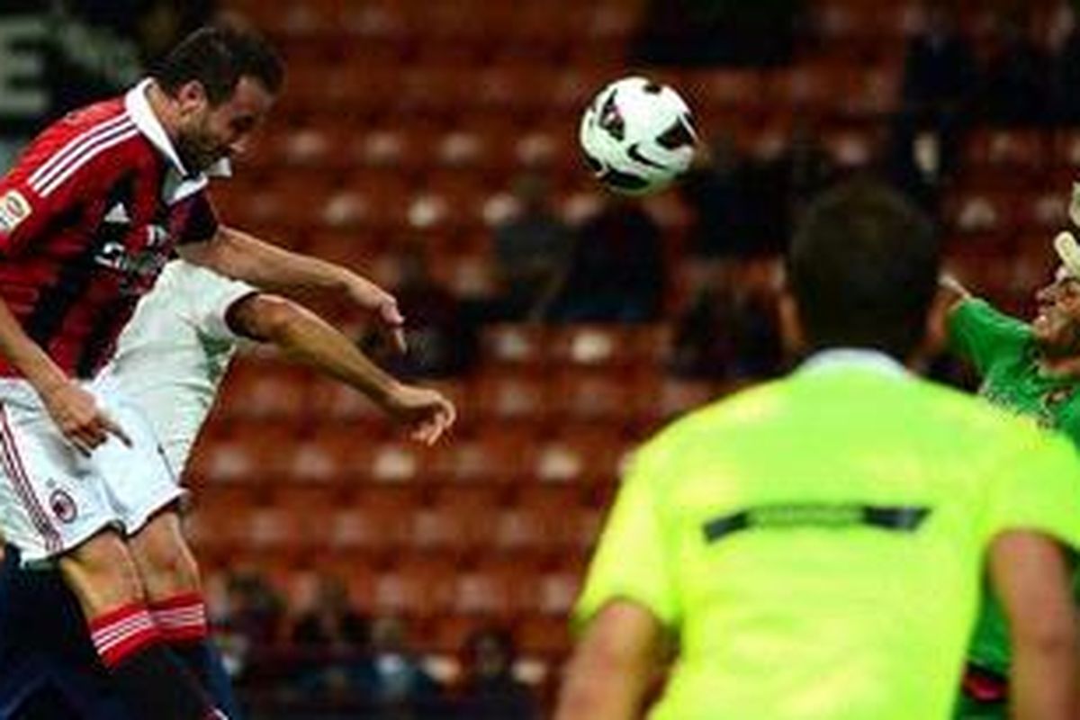 Bomber AC Milan, Giampaolo Pazzini (kiri), menanduk bola ke gawang Cagliari yang dikawal Michael Agazzi, dalam laga Serie-A di Stadion San Siro, Rabu (26/9/2012). Milan akhirnya menang 2-0.