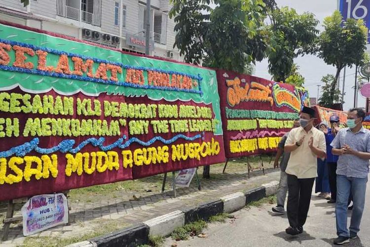 Ketua DPC Partai Demokrat Pekanbaru Agung Nugroho dan pengurus saat melihat karangan bungan ucapan selamat atas ditolaknya KLB kubu Moeldoko, yang dipajang di kawasan kantor DPC Demokrat Pekanbaru di Jalan Arifin Achmad, Kota Pekanbaru, Riau, Kamis (1/4/2021).