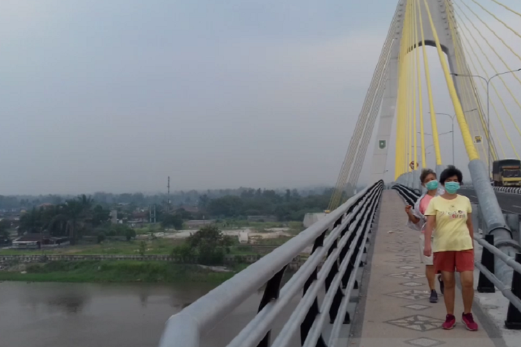 Dua orang berolahraga pagi di Jembatan Siak IV, Pekanbaru. Kini, sebagian besi penyangga pagar berwarna hitam itu hilang dicuri orang.