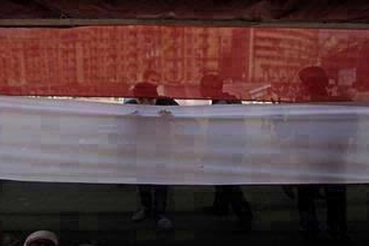 Seorang pemuda mengintip dari balik tenda berwarna seperti bendera Mesir di Lapangan Tahrir, Kairo, Mesir, Selasa (24/1/2012). Rakyat Mesir merayakan peringatan 1 tahun Revolusi 25 Januari 2011.