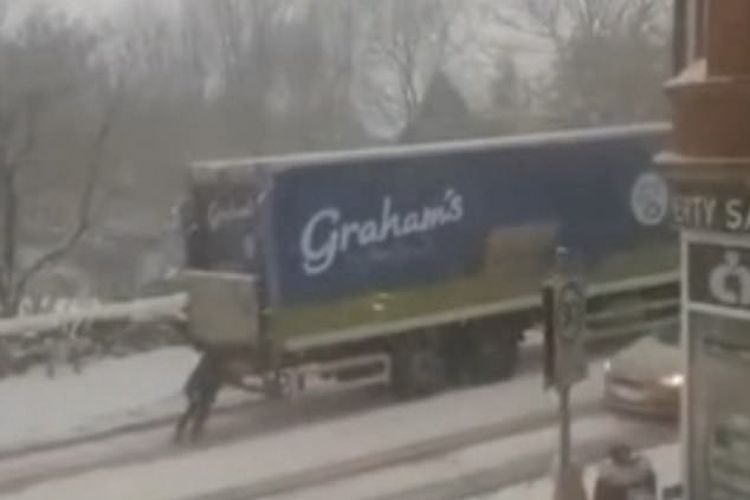 Tangkapan layar Seorang ibu tiga anak, Charlene Leslie (33), membantu mendorong truk susu Graham?s The Family Dairy di jalanan yang tertutup salju di Cowdenbeath, Skotlandia pada Selasa (9/2/2021), saat terjadi Storm Darcy.  