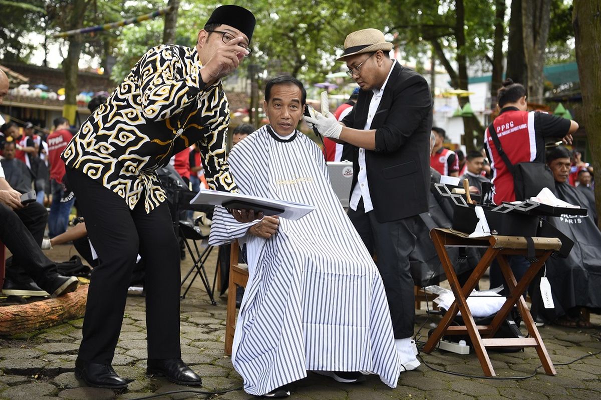 Presiden Joko Widodo (tengah) didampingi Gubernur Jawa Barat Ridwan Kamil (kiri) mengikuti potong rambut massal di area wisata Situ Bagendit, Garut, Jawa Barat, Sabtu (19/1/2019). ANTARA FOTO/Puspa Perwitasari/foc.