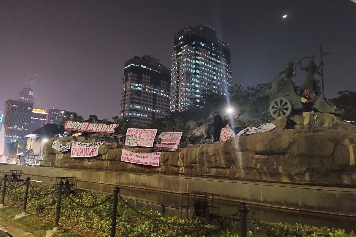 Sejumlah spanduk digantung oleh mahasiswa saat demo di Patung Kuda Arjuna Wijaya, Gambir, Jakarta Pusat, Jumat (20/10/2023) malam. (KOMPAS.com/XENA OLIVIA)
