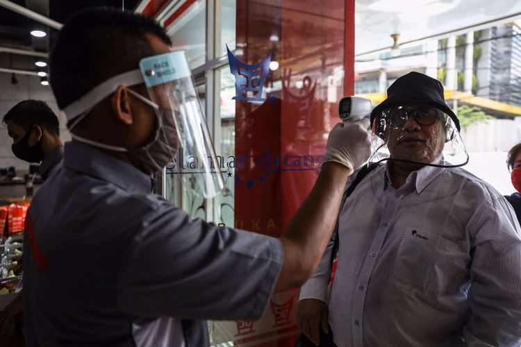 Pelayan mengenakan masker saat memeriksa suhu tubuh pengunjung di Restoran Sederhana, Bendungan Hilir, Jakarta Pusat, Senin (8/6/2020). Sebagai bagian dari rencana penerapan kenormalan baru 8 Juni 2020, pemerintah DKI Jakarta mengharuskan pengusaha rumah makan membatasi kapasitas maksimal 50 persen, larangan penyajian makanan secara prasmanan dan tetap menerapkan protokol kesehatan.