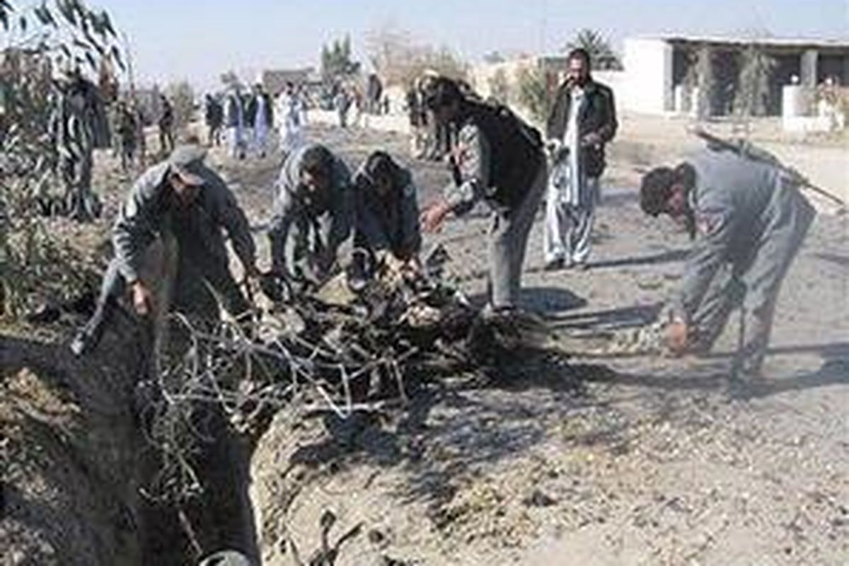 Polisi Afganistan mencoba mengangkat puing-puing kendaraan pelaku bom bunuh diri di sebuah lokasi serangan bunuh diri di Kandahar, 12 Desember 2007. 