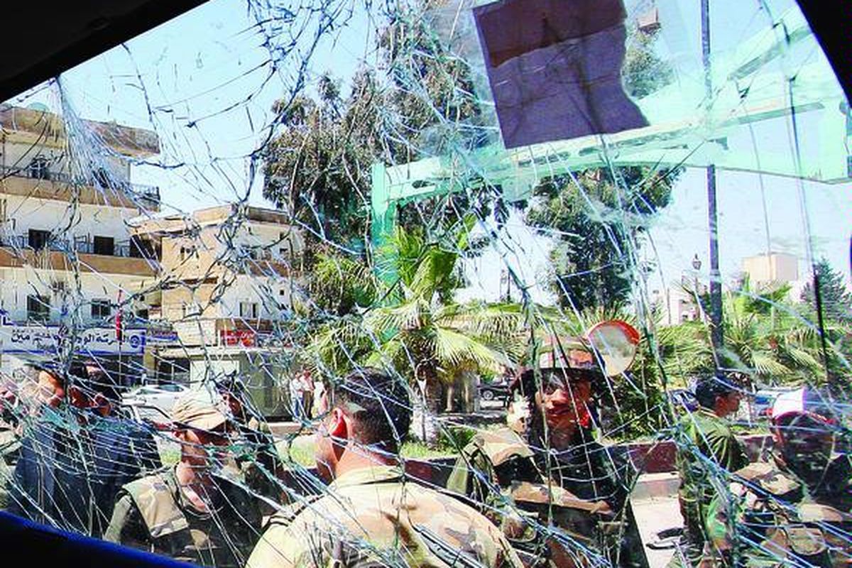 Tentara Suriah mengamati  truk militer yang hancur karena ledakan bom di tepi jalan di Deraa, Suriah selatan, Rabu (9/5). Ledakan yang menimpa truk tersebut terjadi hanya beberapa saat setelah tim pemantau PBB melintas. Tiga tentara Suriah yang terluka tampak dievakuasi dari lokasi kejadian.