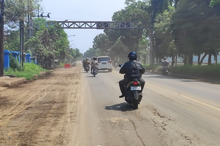 Sisa lumpur yang mengering pasca banjir kiriman yang menutup jalur pantura di Kota Pasuruan membuat polusi udara. Karwna debu beterbangan saat pengendara motor melintas jalir tersebut, Selasa (20/05/2025) 