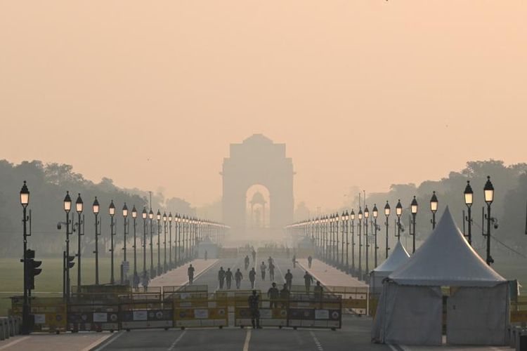 Orang-orang berjalan di sepanjang jalan dekat Gerbang India di tengah kondisi berkabut di New Delhi pada 25 Oktober 2022.