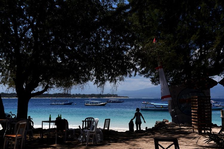 Seorang WNA memungut sampah plastik yang berhamburan di pinggir pantai di Gili Trawangan, Lombok Utara, NTB, Kamis (9/8). Kondisi pulau wisata tersebut sepi pascagempa yang terjadi pada 5 Agustus lalu,  meski sejumlah WNA dan warga lokal masih bertahan di pulau itu. ANTARA FOTO/Zabur Karuru/aww/18.