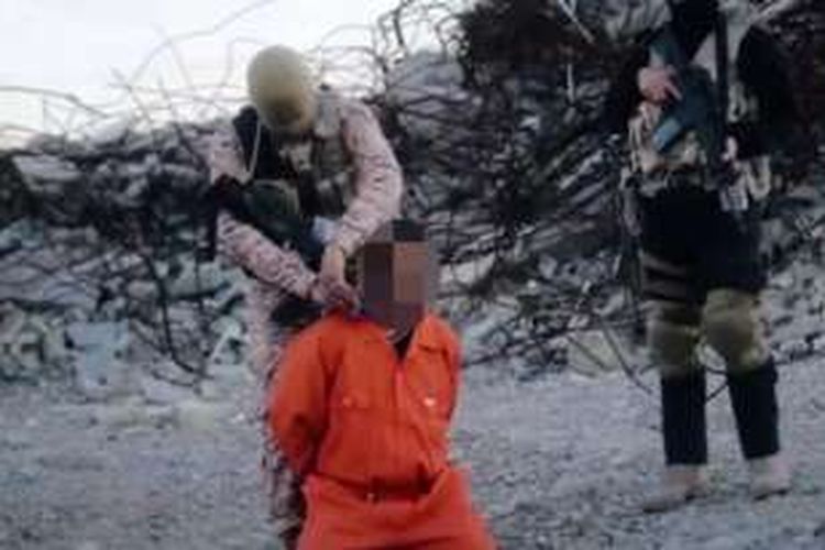 Dalam foto yang diambil dari video terbaru yang dirilis ISIS, terlihat seorang anggota kelompok itu melilitkan bahan peledak di leher seorang tawanan yang disebut sebagai mata-mata Irak.