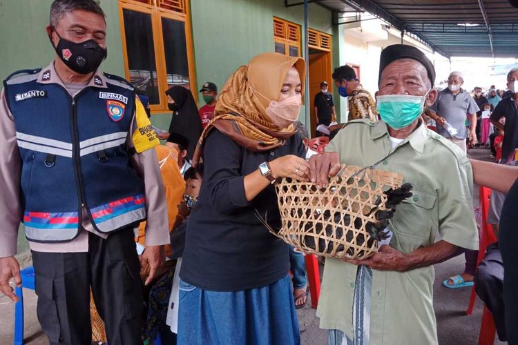 Mbah Sandi (80) menerima seekor ayam kampung hadiah dari panitia vaksinasi Covid-19 massal di Balai Desa Mertoyudan, Kecamatan Mertoyudan, Kabupaten Magelang, Jawa Tengah, Kamis (28/10/2021),