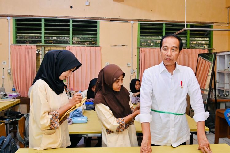 Presiden Joko Widodo mengikuti arahan dari siswi-siswi SMK Negeri 4 Jambi saat mengukur ukuran kemeja yang dipesannya pada Selasa (16/5/2023). Presiden memesan kemeja putih dari siswa-siswi jurusan tata busana sekolah tersebut.