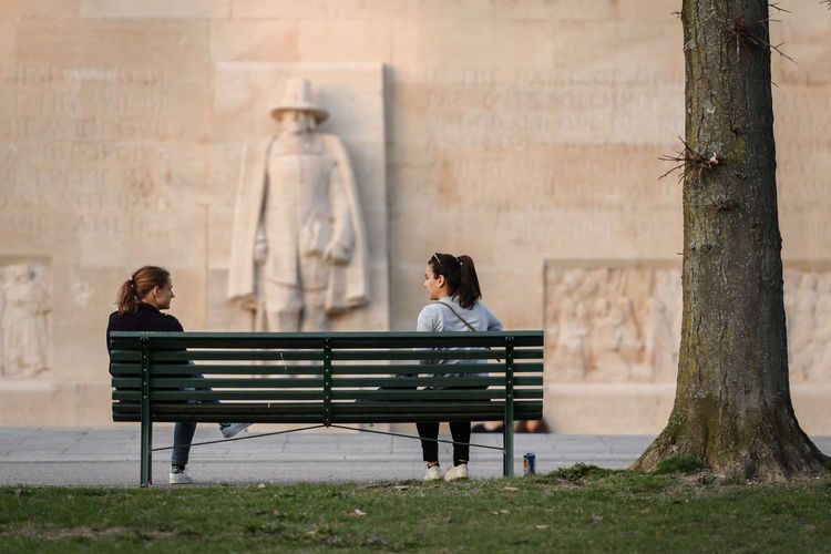 Dua orang wanita menjaga jarak sosial saat mengobrol di kursi taman di Jenewa, Swiss, 18 Maret 2020. Menjaga jarak aman antar warga merupakan salah satu cara yang dianjurkan untuk mencegah penyebaran virus corona.