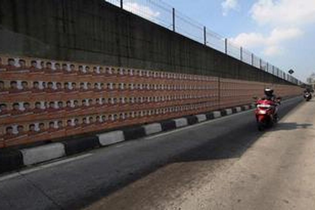 Poster kampanye salah satu pasangan calon gubernur dan wakil gubernur terpasang hampir 20 meter lebih panjangnya di dinding fly over sisi jalur bus TransJakarta di kawasan Pancoran, jakarta, Rabu (13/6/2012). Poster dan selebaran serupa banyak dipasang di fasilitas umum menjelang Pilkada DKI. 