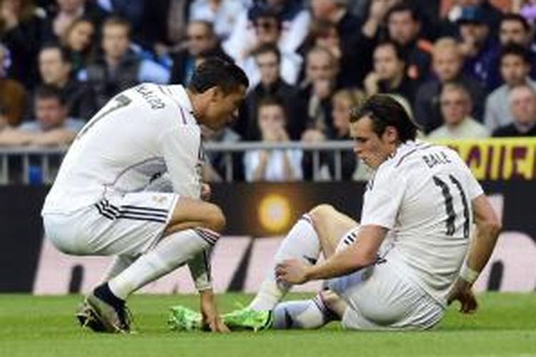 Penyerang Real Madrid Gareth Bale (kanan) duduk sambil memegang betisnya yang bermasalah. Sementara itu Cristiano Ronaldo menghampirinya, dalam laga melawan Malaga di Santiago Bernabeu, Sabtu (18/4/2015).